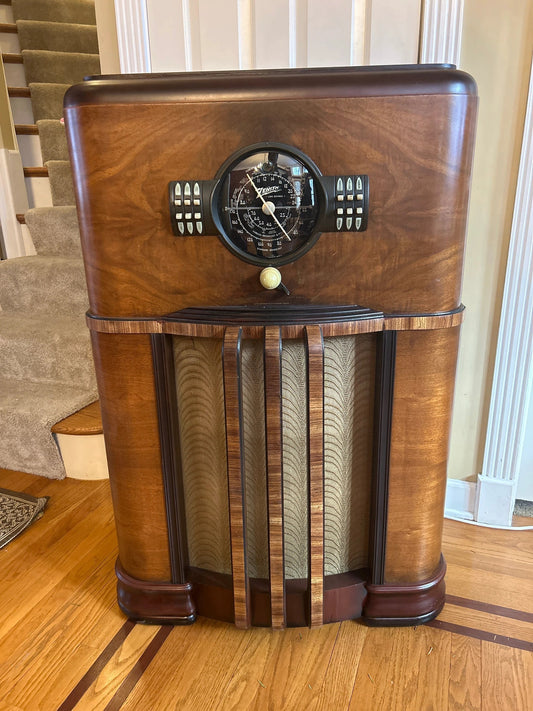 Wooden wall-mounted shelf with a clock and radio receiver in a room with wooden paneling.