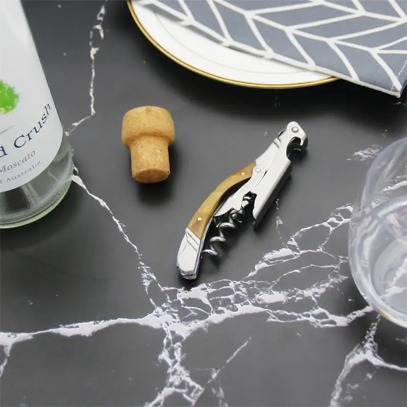 Cork, corkscrew, and bottle on a marble surface