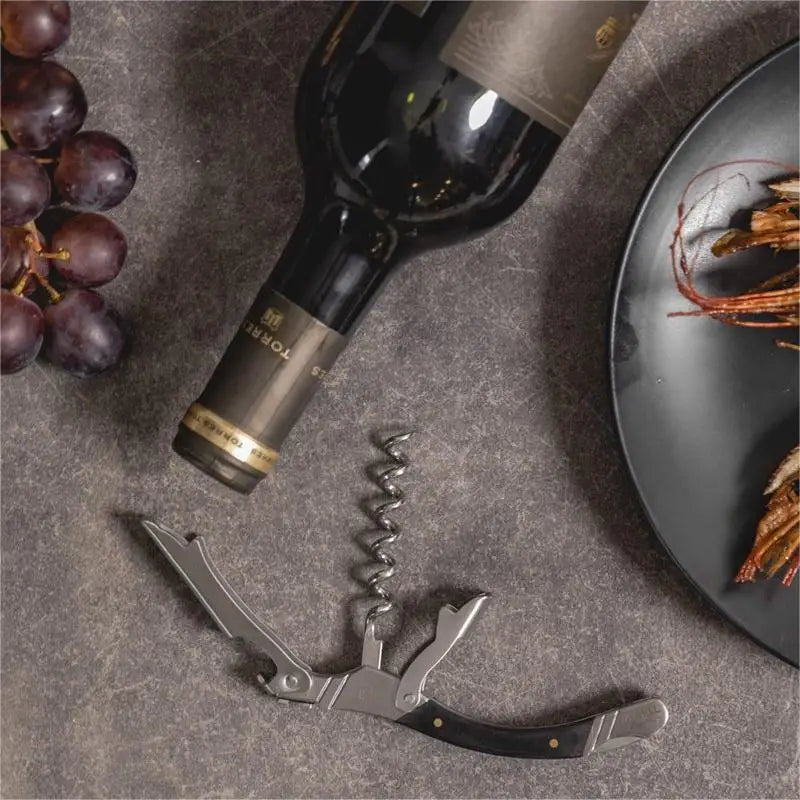 Wine bottle, corkscrew, and grapes on a textured surface