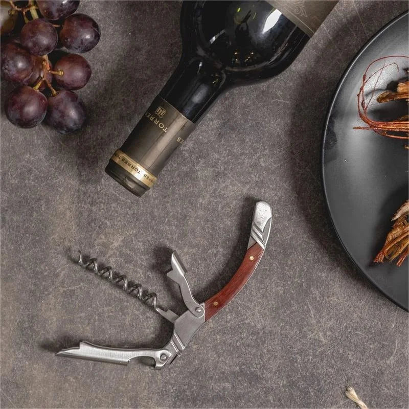 Wine bottle, corkscrew, and grapes on a textured surface