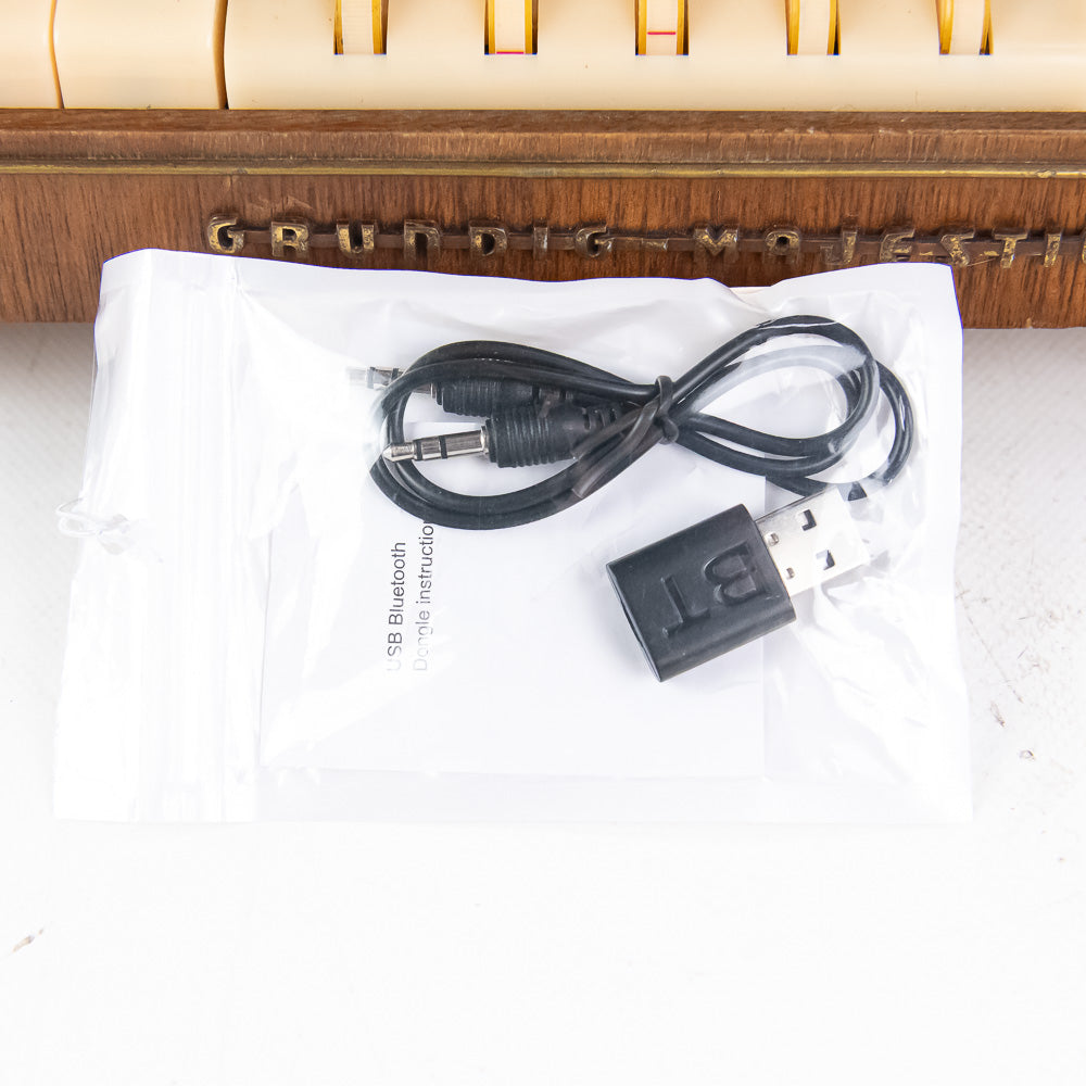 USB cable and adapter on a white surface with a wooden product in the background