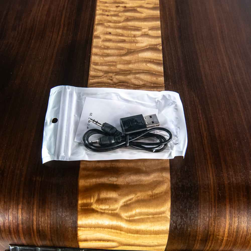 Packaged audio cable with plug and USB connector on a wooden surface