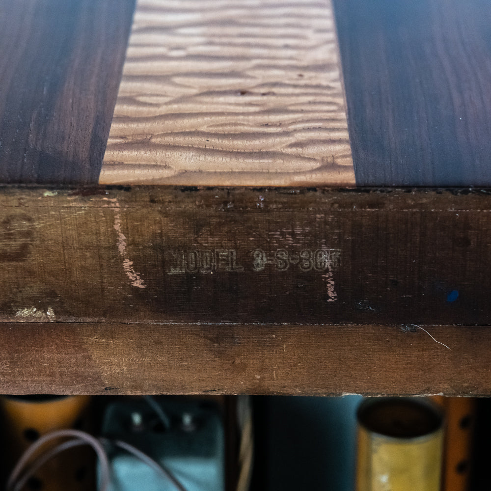 Wooden surface with engraved text 'MODEL 3-S-3GF' on a blurred background